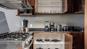 Een moderne keuken met roestvrijstalen apparatuur, houten kasten en een inbouwplank met servies en kookgerei.