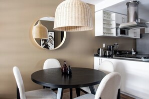 A modern kitchen with white cabinets, a stainless steel range hood, and a round dining table with four chairs. - 4 BR in 2 beautiful apartments (Ciudad de México)