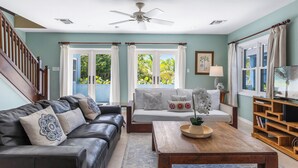 A living room with a sofa, coffee table, and TV stand. - Pease Bay Manor is a private, secluded beachfront villa - call Cayman Villas (Bodden Town)