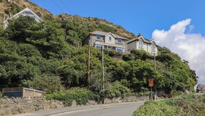 Un quartier résidentiel situé sur une colline, avec des maisons, une route et un mur en pierre.