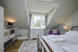 Cozy loft-style room with a large window, wooden bed, and a stylish dresser.