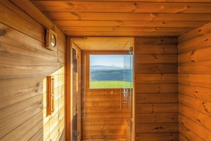 A wooden interior with a door leading to a view of a green landscape.