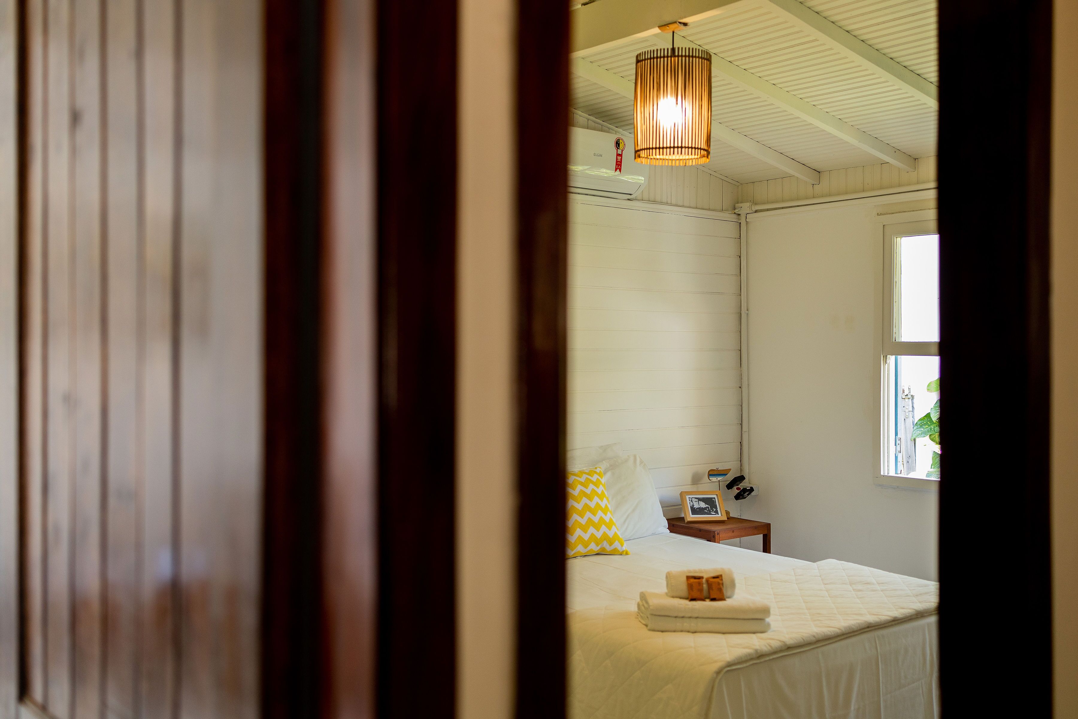 A bedroom with a bed, a bedside table, a lamp, and a window.