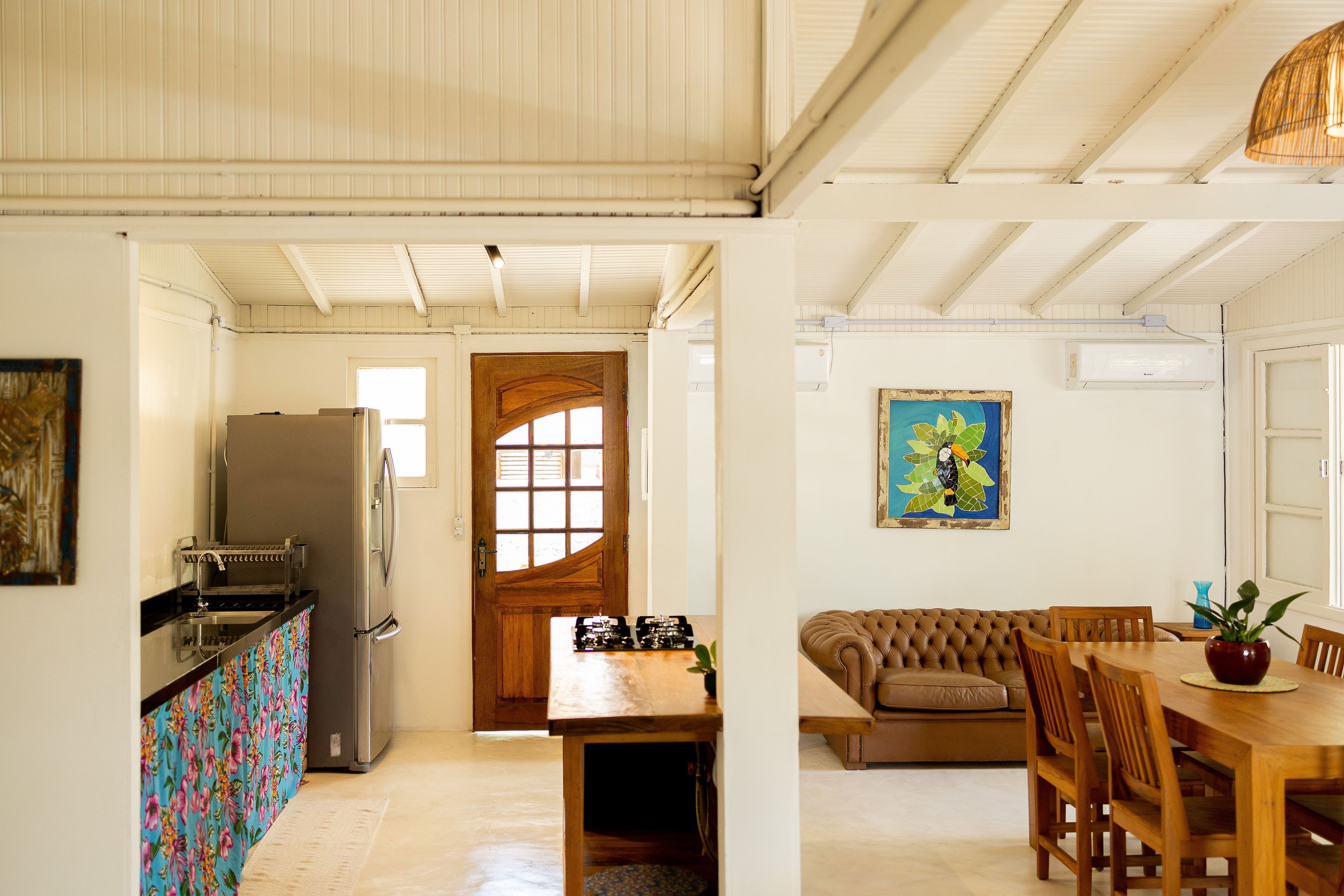 Una cocina equipada con refrigerador, estufa y pileta. Cuenta con un comedor con mesa y sillas, y un sofá.