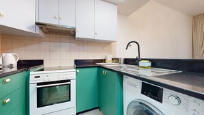 Uma cozinha compacta com forno Siemens, máquina de lavar e pia com torneira.
