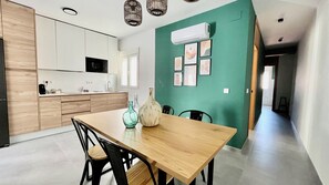 Cozinha moderna com armários brancos, uma mesa de jantar de madeira e uma parede verde.