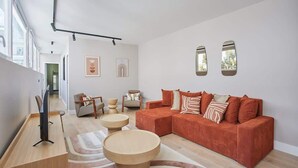A modern living room with a large sofa, two round coffee tables, and a flat-screen TV. - Sublime and new apartment Le Marais / Beaubourg (Paris)