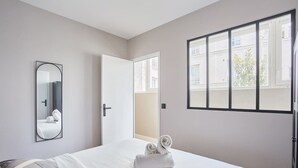A hotel room with a bed, a mirror, a window, and a door. - Sublime and new apartment Le Marais / Beaubourg (Paris)