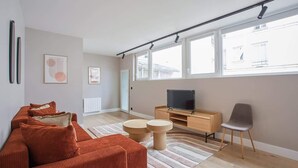 A modern living room with a sofa, a TV, a wooden cabinet, and a chair. - Sublime and new apartment Le Marais / Beaubourg (Paris)