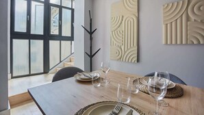 A dining area with a wooden table set for four, a black decorative piece, and abstract wall art. - Sublime and new apartment Le Marais / Beaubourg (Paris)
