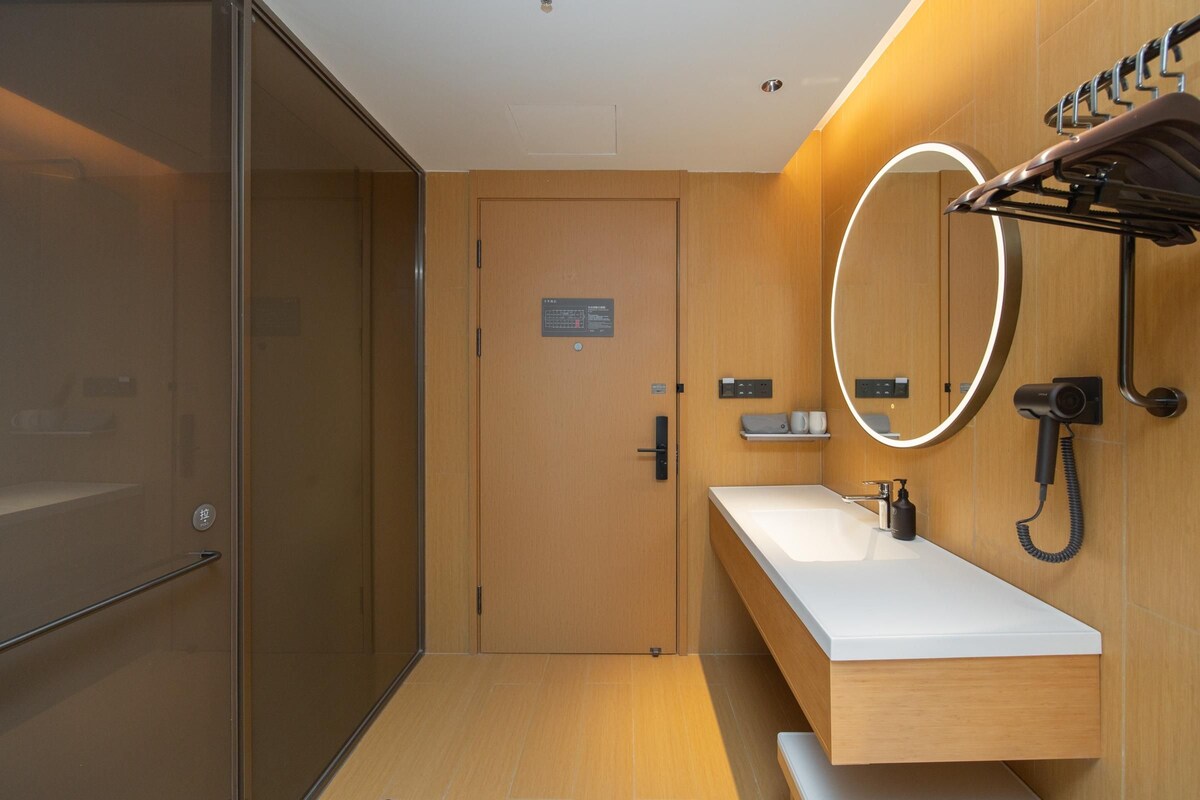 A modern bathroom with a wooden vanity, a mirror with a circular frame, and a towel rack.