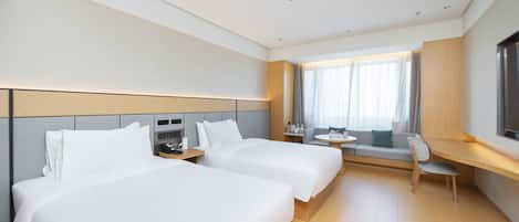 A hotel room with two beds, a desk, a chair, and a TV.