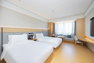 Una habitación de hotel con dos camas, un escritorio, una silla y un televisor.