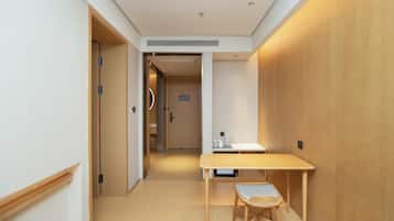 Una habitación de hotel con una mesa y silla de madera, una pequeña cocina y una puerta que da a otra habitación.