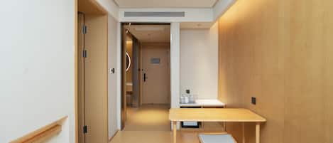 Una habitación de hotel con una mesa y silla de madera, una pequeña cocina y una puerta que da a otra habitación.