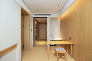 Ein Hotelzimmer mit Holztisch und Stuhl, einer kleinen Küchenzeile und einer Tür zu einem weiteren Raum.