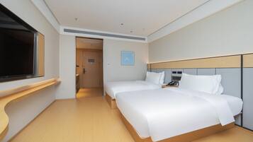A modern hotel room with two beds, a TV, and a wooden floor.