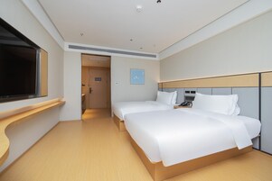 Una habitación de hotel moderna con dos camas, televisión y suelo de madera.