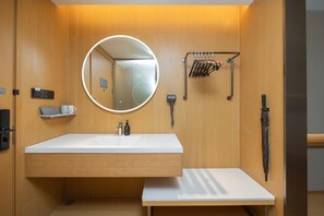 A modern bathroom with a white sink, a round mirror, a towel rack, and a shower area. - Ji Hotel Hefei Mingzhu Square (Hefei)