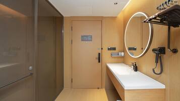 Un baño moderno con tocador de madera, un espejo con luz circular y un perchero para toallas.