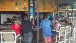 An outdoor bar area with a counter, chairs, and a decorative wall. - Renovated Beach Front Studio - Hawaiian Inn Resort (Daytona Beach Shores)