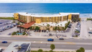 A hotel with a curved facade, parking lots, and a view of the ocean. - Renovated Beach Front Studio - Hawaiian Inn Resort (Daytona Beach Shores)