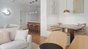 Un salon moderne comprenant un canapé, une table à manger avec des chaises et un coin cuisine avec des tabourets.