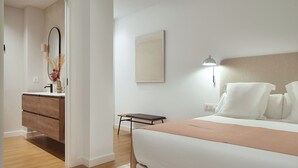 Une chambre à coucher avec un lit, une table de chevet, une lampe et une vue sur la salle de bain.