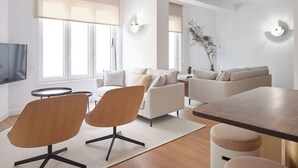 Un salon moderne comprenant un canapé, deux fauteuils, une table basse et un téléviseur.