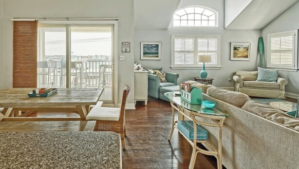 A spacious living room with a dining area, large windows, and a high ceiling. - Bright and Airy Condo.  One block to the Beach.  Great location. (Sea Isle City)