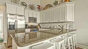 A kitchen with white cabinets, a granite countertop, a stainless steel refrigerator, a microwave, and a sink with a faucet. - Bright and Airy Condo.  One block to the Beach.  Great location. (Sea Isle City)