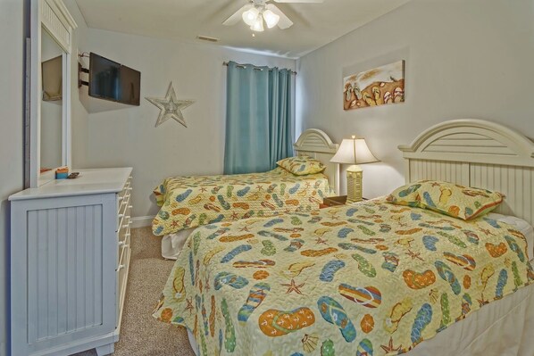 A bedroom with two beds, a dresser, a star decoration, a lamp, and a painting on the wall.