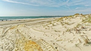 A sandy beach with footprints and sparse vegetation. - Bright and Airy Condo.  One block to the Beach.  Great location. (Sea Isle City)