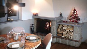 A cozy dining area with a fireplace, a Christmas tree, and a table set for four.