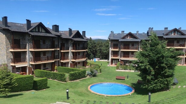A multi-story hotel with balconies, a swimming pool, and well-maintained lawns.