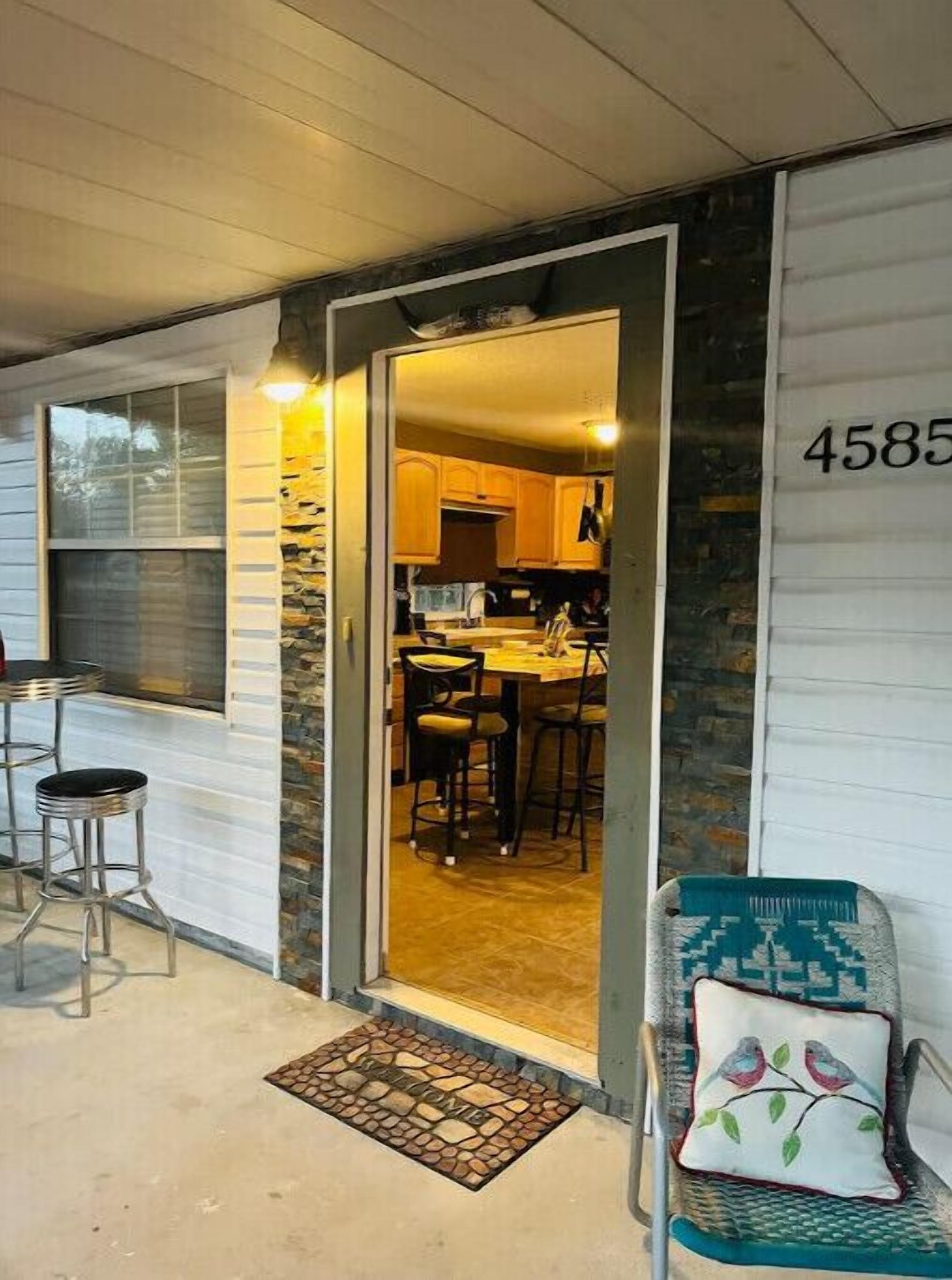Il s’agit d’une maison avec une façade en pierre, une cuisine dotée de meubles en bois et un coin repas équipé de tabourets de bar.