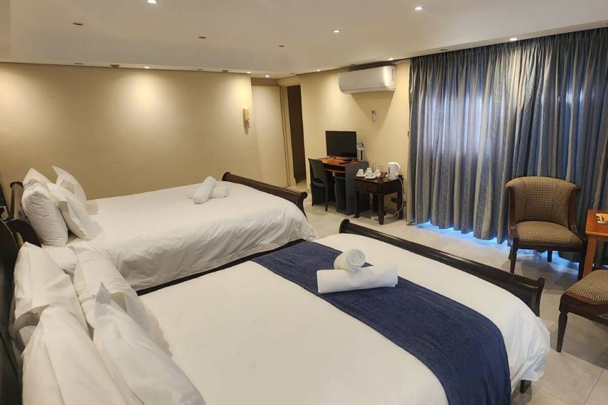 Camera d'albergo con due letti, una scrivania, una sedia e una televisione.
