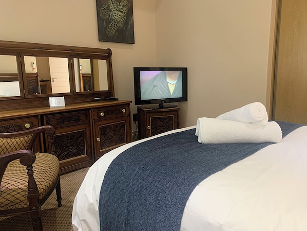 Una habitación de hotel con una cama grande, un aparador de madera, un televisor y una silla.