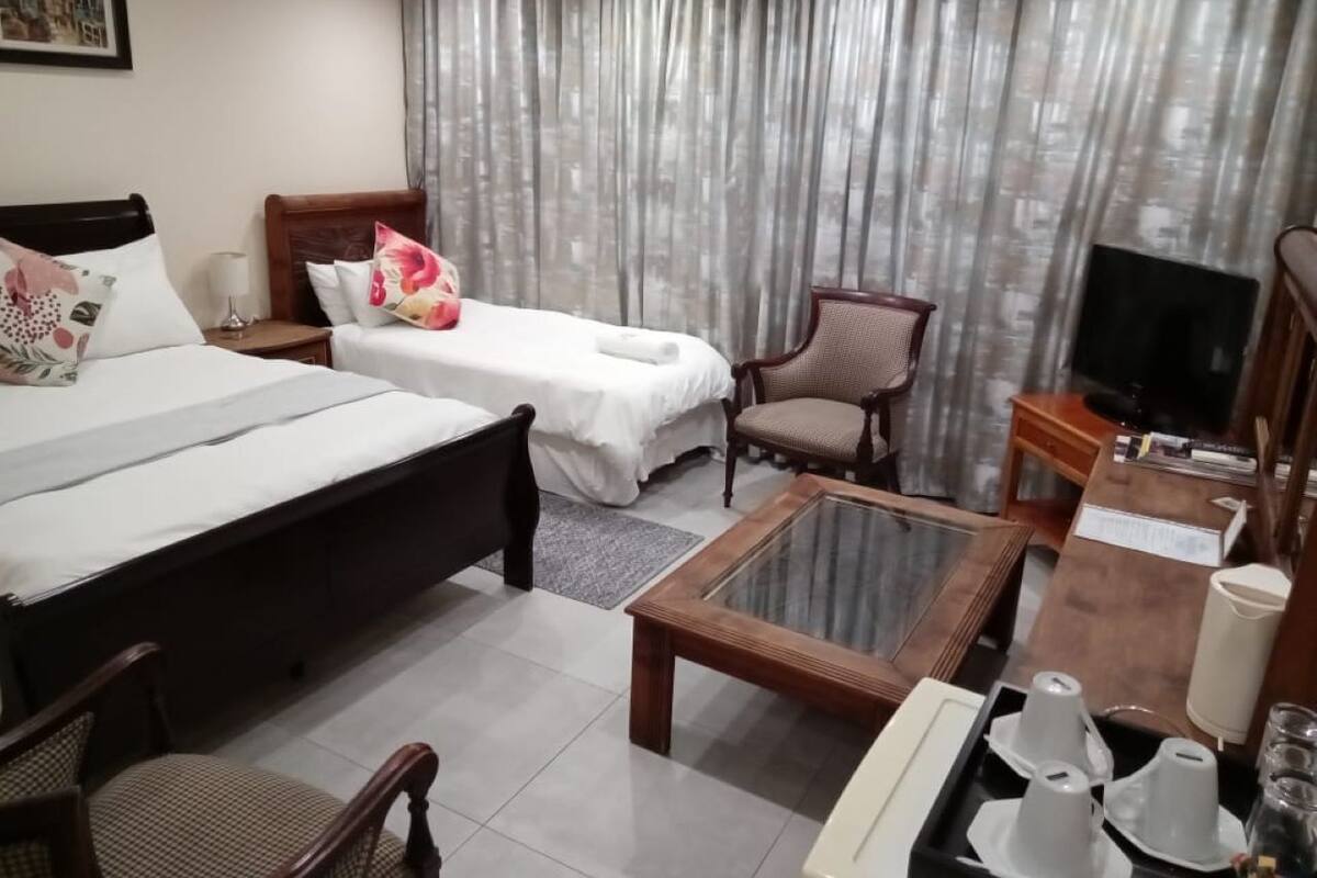 Camera d'albergo con due letti, una televisione, un tavolino e una sedia.