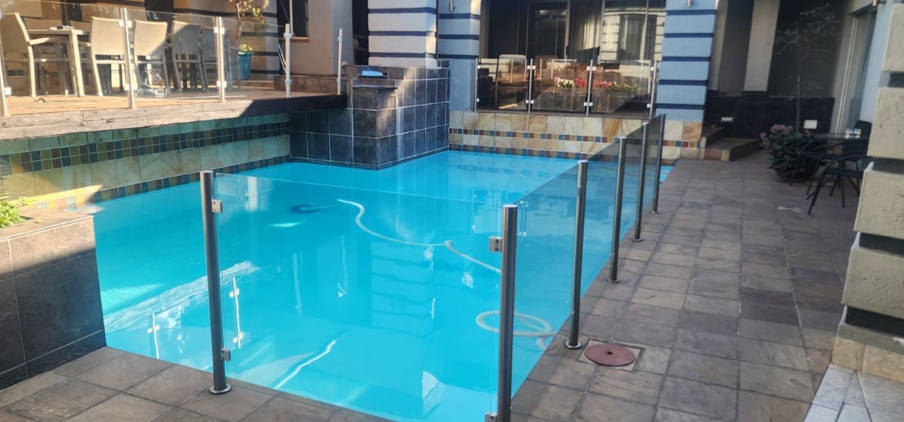 Une piscine dotée d’une terrasse carrelée, entourée de mobilier d’extérieur et d’un sol recouvert de dalles de pierre.