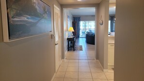A hallway leading to a living area with a dining table, chairs, and a view of the outside. - Luxury 3 Bed 2 Bath in FMB! Beach & Pool with the BEST reviews! (Fort Myers Beach)