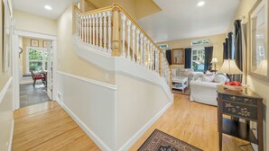 Eine Treppe mit weißen Balustern, einem Holzboden, einem weißen Sofa und einer Lampe.