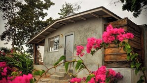 Una casa con fachada de concreto, terraza de madera y puerta principal.