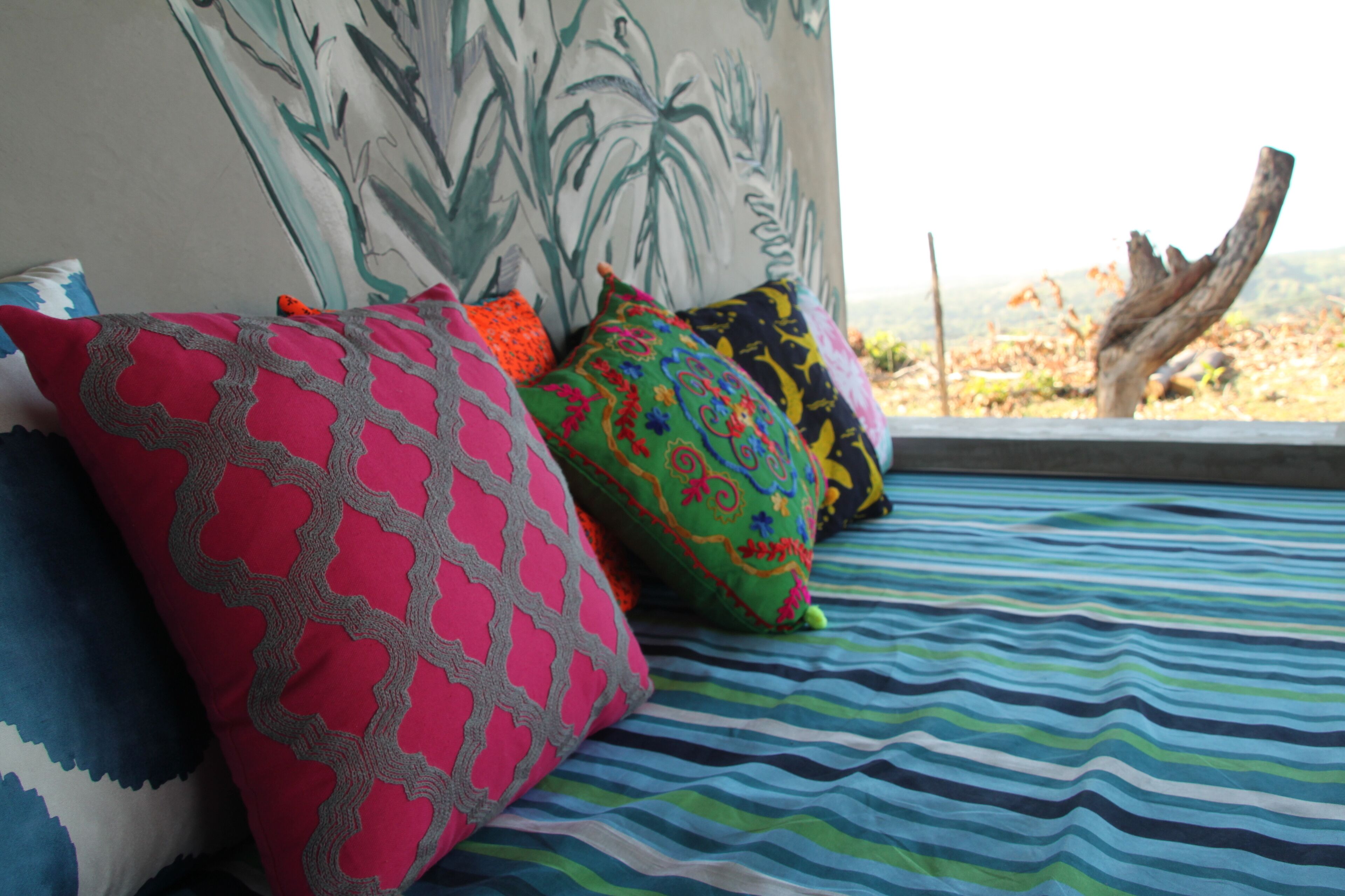 A bed with colorful pillows and a striped bedspread.