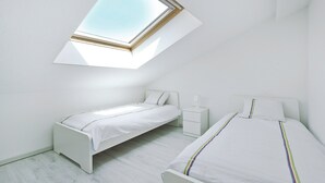 Een slaapkamer met dakraam, twee bedden, een nachtkastje en een bijzettafeltje.