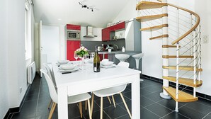 Een moderne keuken met een witte eettafel, een spiltrap en een rode accentmuur.