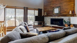 A modern living room with a large sofa, a fireplace, and a television. - 2 Bedroom Montezuma Condo at Lakeside Village - Shuttle to Slopes! (Keystone)