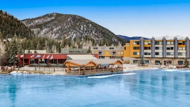 A hotel with a pool, wooden deck, and mountain backdrop. - 2 Bedroom Montezuma Condo at Lakeside Village - Shuttle to Slopes! (Keystone)
