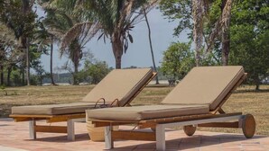 Two lounge chairs by a poolside with a view of palm trees and a clear sky. - Savanna Orinoquia Lodge (Orocue)
