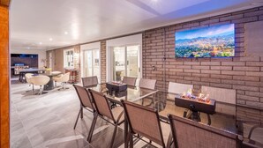 A modern dining area with a glass table, comfortable chairs, and a cityscape TV on the wall. - Luxury 4 Bed/4Bath! Private Pool & Mountain Views! (Phoenix)